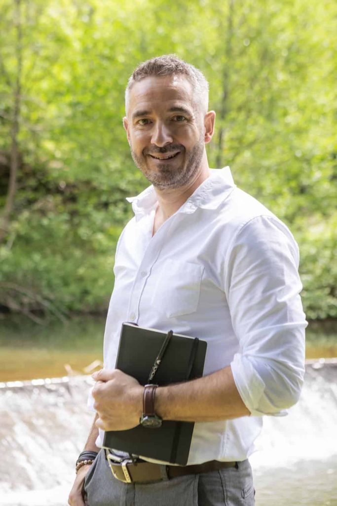 Etienne Couzinier, souriant avec son carnet. Coach professionnel dans le Tarn : accompagnement en présentiel et distanciel des particuliers et des structures médico-sociales